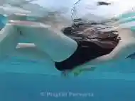 Girl in one piece swimsuit in pool has tied hands with rope