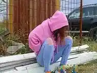 Hipster redhead changes wet clothes and pee outdoor - Girl with a hoodie pee trough her jeans