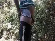 A young, pot-bellied guy peeing in the woods